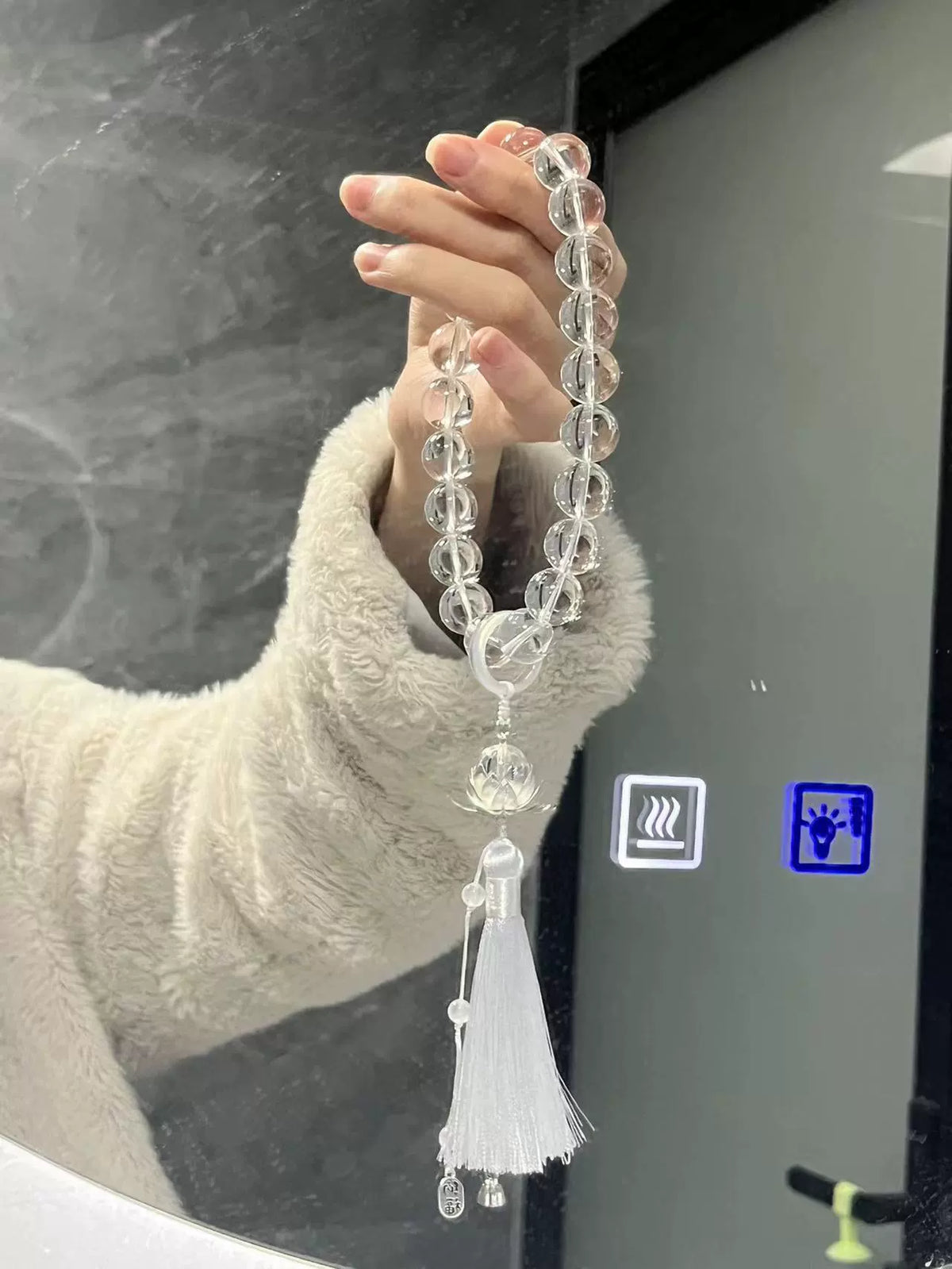 Clear glass bead handheld loop with a transparent ring, lotus-shaped pendant and white thread tassel.