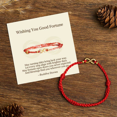 Red string bracelet with a brass infinity charm and a message card