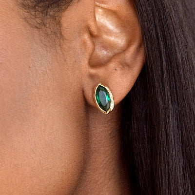 Model wearing a green marquise CZ stud with a gold-tone rim.