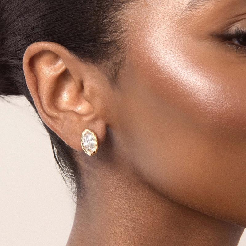 model wearing a clear marquise stud with a gold-tone setting.